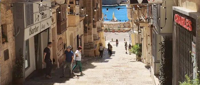 Paisaje en las calles de Malta, donde se observan fachadas y al fondo se aprecia el mar mediterraneo.