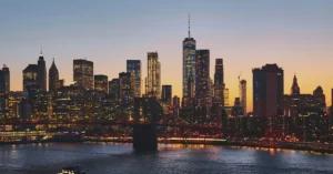 Paisaje urbano al anochecer en Nueva York donde se ven los edificios con luces.