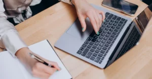 Mujer con manos femeninas usando un computador con IA para aprender inglés